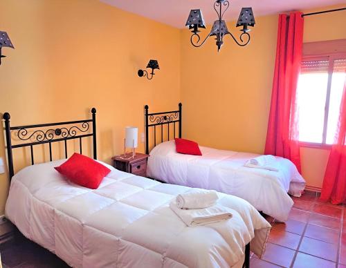 a bedroom with two beds with red pillows at Casa Vaélico in Arenas de San Pedro