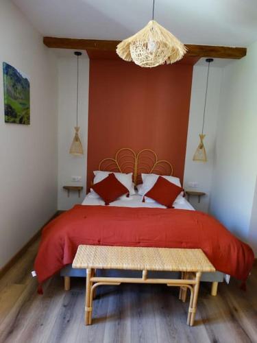 a bedroom with a bed with a red comforter at Gîte Chez Arnaoutou in Beaudéan