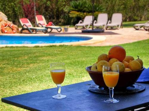 een fruitschaal op een tafel met twee glazen sinaasappelsap bij Ciclismo y golf junto a la playa Finca Son Sant Martí Gran in Muro