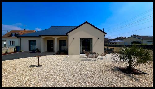 une maison avec deux chaises devant elle dans l'établissement Villa Saint Mart, Saint Martin de Bréhal, 500m de la mer, à Saint Martin de Brehal