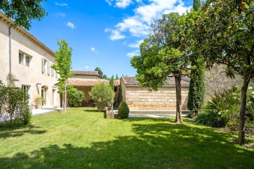 une cour d'une maison avec de l'herbe et des arbres dans l'établissement Mas ARAGON - XVIIIème - Piscine & Jardin paysager, aux Angles (Gard)