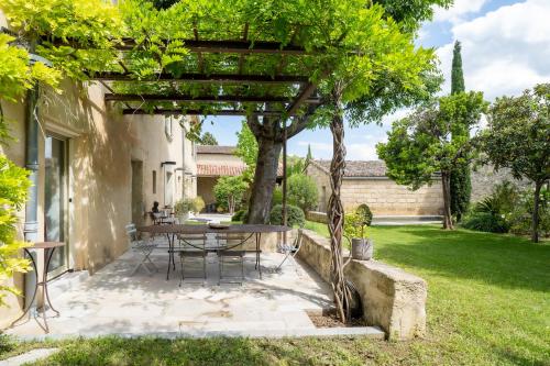 une table et des chaises sous une pergola dans une cour dans l'établissement Mas ARAGON - XVIIIème - Piscine & Jardin paysager, aux Angles (Gard)