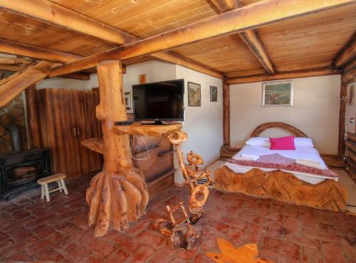 a bedroom in a log cabin with a bed and a television at Ethno Village Dolina Mira in Pale