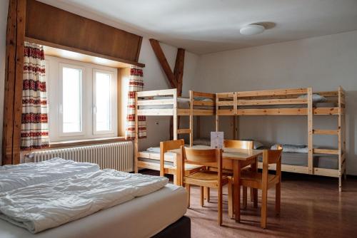 1 dormitorio con cama, mesa y literas en Gruppenhaus Lindenhof Churwalden, en Churwalden