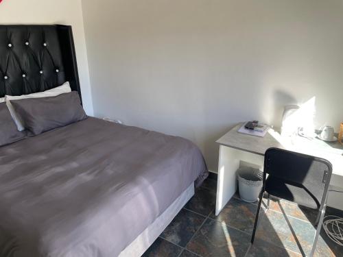 a bedroom with a bed and a desk with a chair at SapzRes at Klerksdorp in Klerksdorp