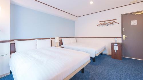 a hotel room with two beds and a door at Toyoko Inn Shin-Osaka-eki Higashi-guchi in Osaka