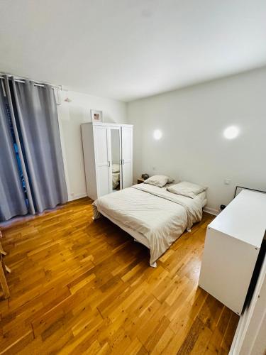 une chambre avec un lit et un parquet dans l'établissement Belle maison avec jardin expose plein sud proche centre ville, à Caen