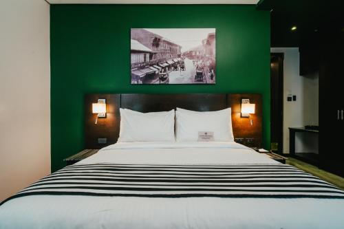 a bedroom with a large bed with a green wall at 1898 Hotel Colonia En Las Filipinas in Manila