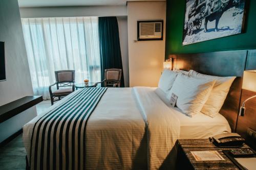 a hotel room with a large bed and a desk at 1898 Hotel Colonia En Las Filipinas in Manila
