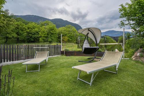 three chairs and an umbrella in a yard at Wiesgut Apartment Stark in Tesimo