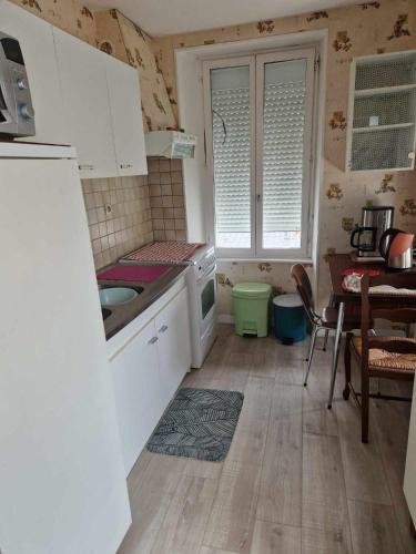 une cuisine avec des armoires blanches, une table et un évier dans l'établissement Saint Pair sur Mer 50 m de la plage, à Saint-Pair-sur-Mer