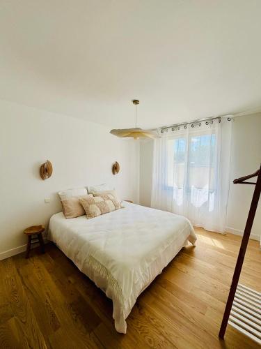 une chambre blanche avec un grand lit et une fenêtre dans l'établissement La Petite Maison du Quai - face à la sèvre, à Niort