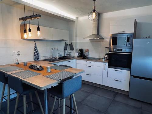 - une cuisine avec des placards blancs, une table et un réfrigérateur dans l'établissement L'Escale, à Clermont-Ferrand
