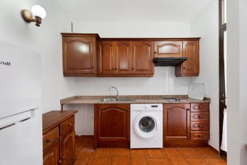 a kitchen with wooden cabinets and a washing machine at Bonita Casa Nieves by Paramount Holidays in Alajeró