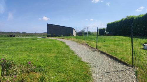 a fence next to a grassy field with a path at Brocéliande calme breton, spa, wifi, amazon-disney tv, 4 lits, Freebox revolution,draps, café, thé in Guer