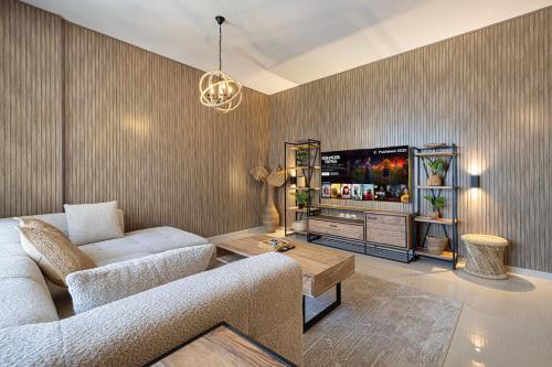 a living room with a couch and a tv at 2BHK Al Zahia Apartment, Sharjah - Boho Nest in Sharjah