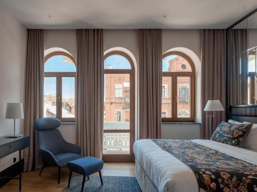 a bedroom with a bed and a chair and windows at Puris Moedani Boutique Hotel in Tbilisi City
