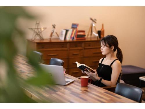 Eine Frau, die an einem Tisch sitzt und ein Buch liest. in der Unterkunft Hotel Emit Shibuya - Vacation STAY 40886v in Tokio