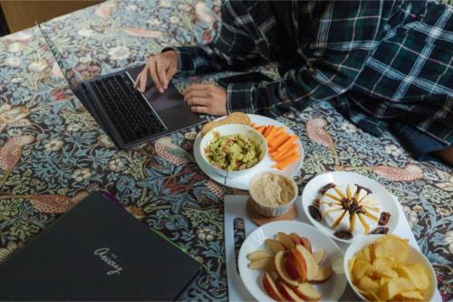 a person sitting on a table with a laptop and food at Tranquility Tiny House by Tiny Away in Owaka