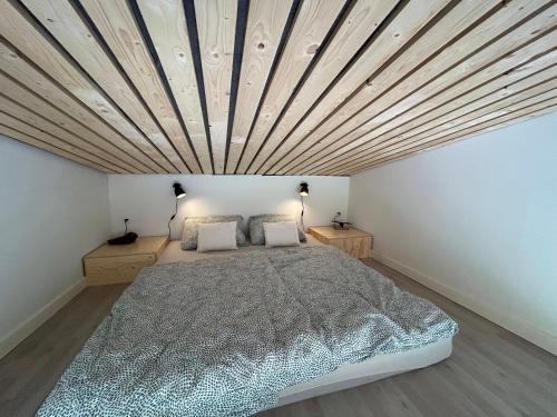 een slaapkamer met een groot bed en een houten plafond bij Tinyhouse in Væggerløse
