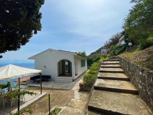 una piccola casa bianca su una collina con l'oceano di Villa Porticciolo - ArgonautiVacanze a Rio Marina