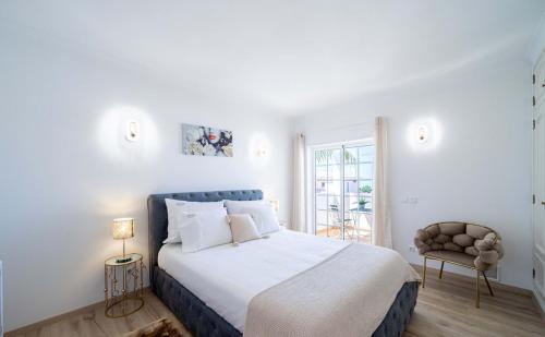 a white bedroom with a large bed and a window at Villa Ílios - Porto de Mós, Lagos in Lagos