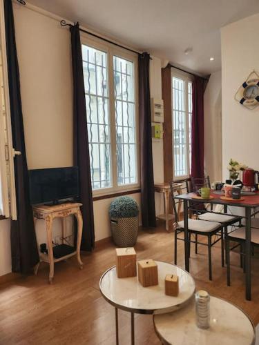 - un salon avec des tables, des chaises et des fenêtres dans l'établissement Logement entier 2p, à Paris