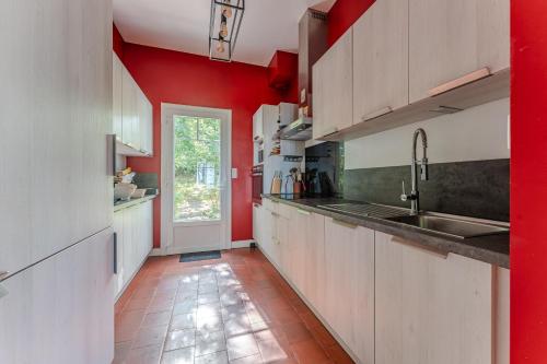 - une cuisine avec des placards blancs et des murs rouges dans l'établissement Pyla Sur Mer Villa 150m Vue Bassin, à La Teste-de-Buch