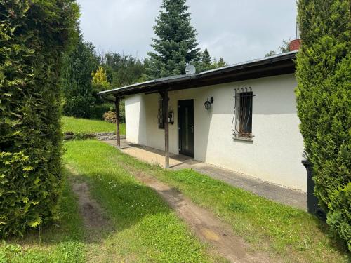 a white building with a door and a yard at Schickes Ferienhaus, freistehend, direkte Waldlage, Terrasse, Kamin, Garten, WLAN in Wienrode