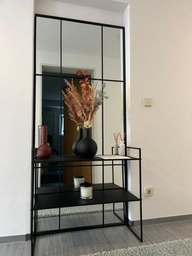 a black shelf with a vase with flowers on it at Deluxe Apartment Ella in Backnang