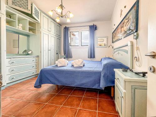 Un dormitorio con una cama azul con toallas. en Perla Del Porto Apartments, en Santa Teresa Gallura