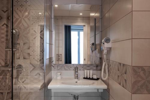 W łazience znajduje się umywalka oraz prysznic z lustrem. w obiekcie Hôtel Saint Martin Bastille w Paryżu