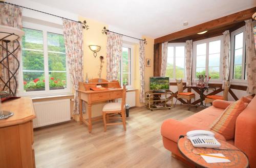 a living room with a couch and a desk and windows at Mosel-Landhaus Hotel Oster in Ediger-Eller