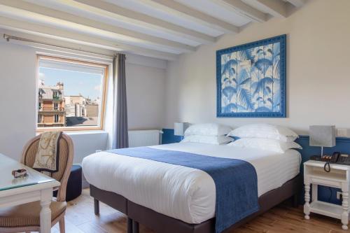 sypialnia z dużym łóżkiem i oknem w obiekcie Hôtel Saint Martin Bastille w Paryżu
