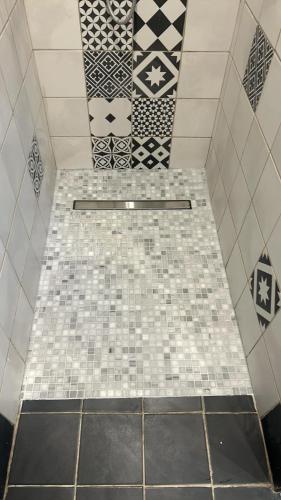 une salle de bain avec un sol carrelé et un mur carrelé dans l'établissement La Forge d'Espérance, à Éperlecques