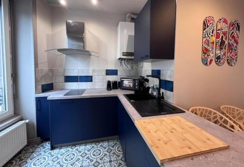 Elle comprend une petite cuisine avec des placards bleus et un évier. dans l'établissement Horus Elegant Gare SNCF 4p, à Clermont-Ferrand
