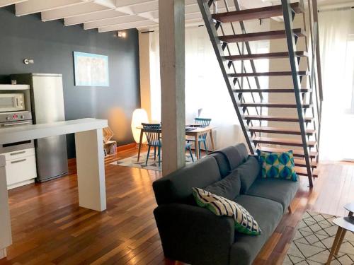 un salon avec un canapé et un escalier en colimaçon dans l'établissement Loft en duplex 4 voyageurs Proche cathédrale, à Reims