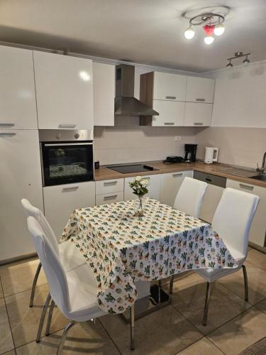 cocina con mesa con sillas blancas y mantel en Apartman BARAKA, en Šibenik