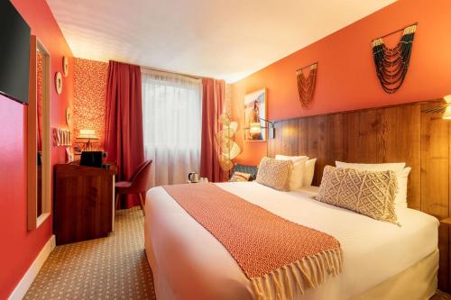 ロワシー・アン・フランスにあるAiden by Best Western Paris Roissy CDGのオレンジ色の壁の大きなベッドが備わるホテルルームです。