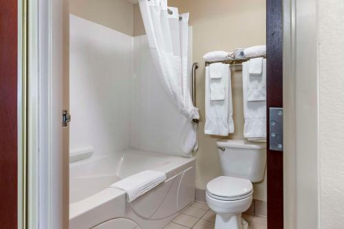 a white bathroom with a toilet and a bath tub at Comfort Suites Grandville - Grand Rapids SW in Grandville