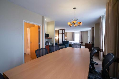 a dining room with a wooden table and chairs at Comfort Suites Airport in Luckney