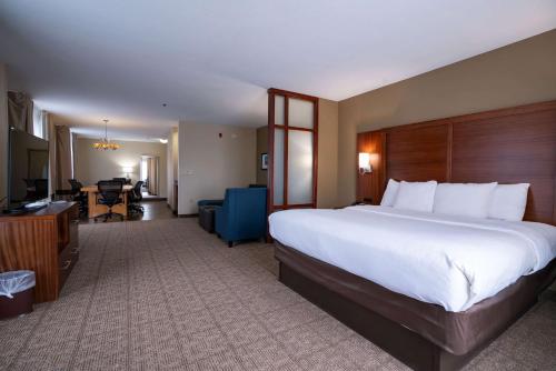 a hotel room with a large bed and a desk at Comfort Suites Airport in Luckney