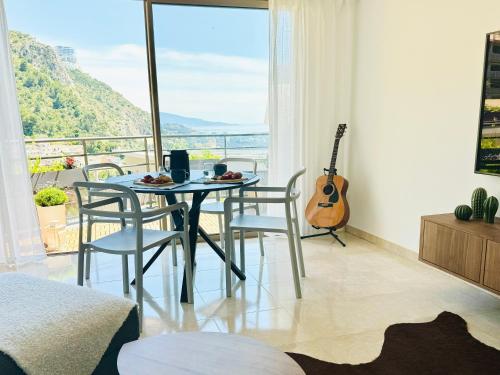 een eetkamer met een tafel en stoelen en een gitaar bij Penthouse over Monaco in Beausoleil