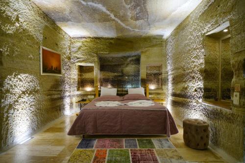 a bedroom with a bed in a stone wall at Göreme Cave Lodge in Goreme