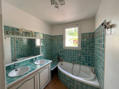 La salle de bains est pourvue de 2 lavabos, d'une baignoire et d'une fenêtre. dans l'établissement Location jolie maison à Lambesc avec piscine et jardin, à Lambesc