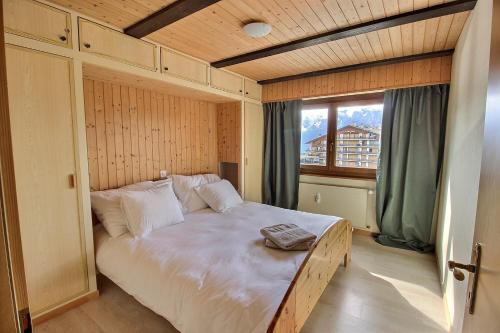 Schlafzimmer mit einem großen weißen Bett und einem Fenster in der Unterkunft Haute Nendaz "Olympic" in Nendaz