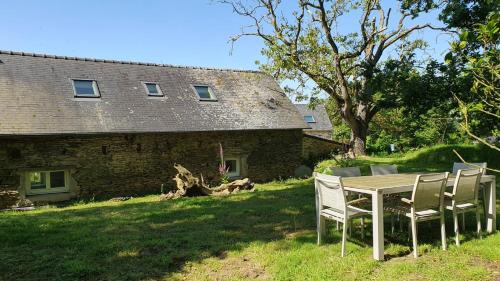 une table et des chaises devant une maison dans l'établissement Les gites de koatephani et ses animaux, à Gouézec