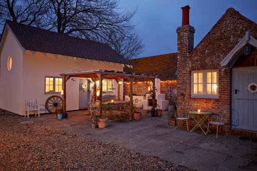 a patio of a house with a table and chairs at The Lodge at Blue Door Barns in Beddingham