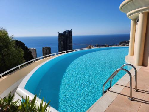 - une piscine au sommet d'un bâtiment avec l'océan en arrière-plan dans l'établissement Spacieux appartement - Parking - Piscine - BV, à Beausoleil