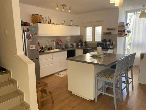 eine Küche mit weißen Schränken und einem Tisch und Stühlen in der Unterkunft Big quiet Cottage in centre Raanana in Ra‘ananna